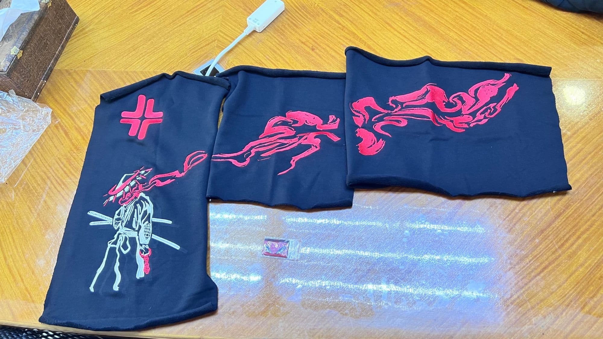 Close-up of the hoodie's embroidered panels: the samurai, red flames, and a red cross mark